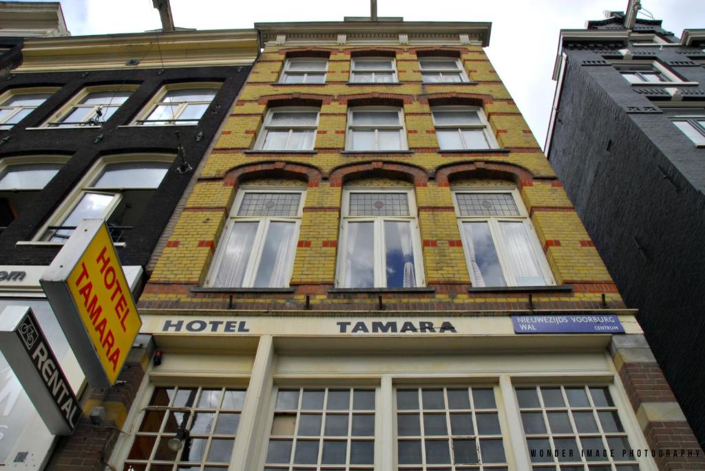 アムステルダムにあるホテル タマラの高いレンガ造りの建物で、ホテルのタマラが飾られています。
