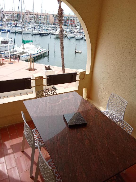 einen Tisch und Stühle in einem Zimmer mit Yachthafen in der Unterkunft superbe appartement vue port in Leucate-Plage