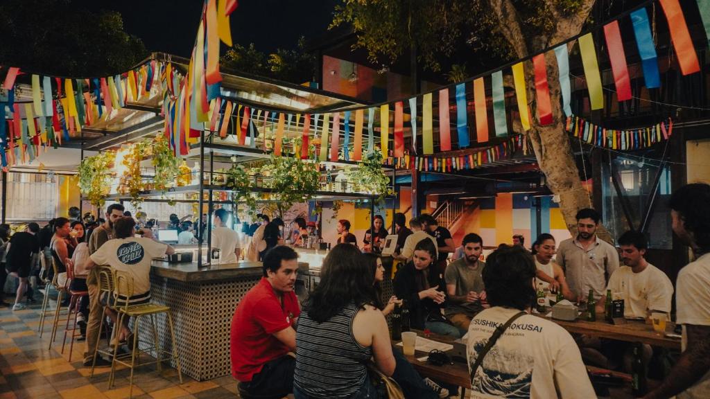 利马Viajero Lima - Barranco Hostel的一群人坐在酒吧里,悬挂着旗帜