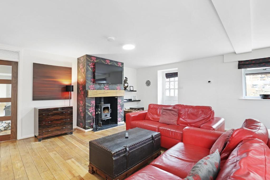 a living room with a red leather couch and a fireplace at Barn Cottage - North East Escapes in Bamburgh