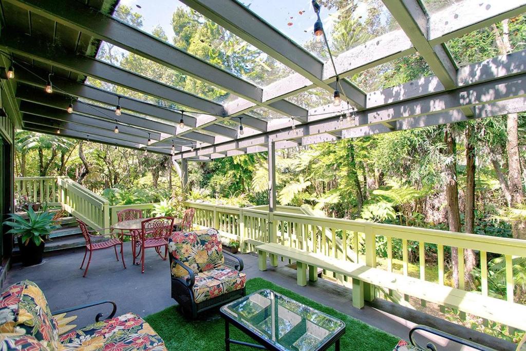 a covered porch with chairs and a table and a table at Halehikiola in Volcano