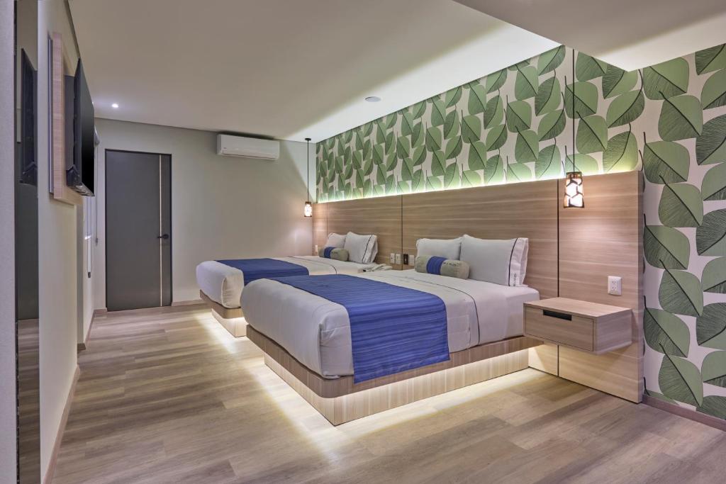 A two-bed room with leafy wallpaper, a wall-mounted television, and air conditioning.