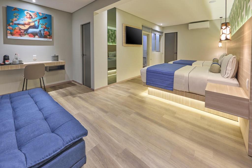 A modern room with one bed, a blue sofa, and a compact desk.
