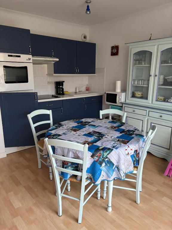 une cuisine avec une table et des chaises dans une cuisine dans l'établissement Appartement proche mer, à Cucq