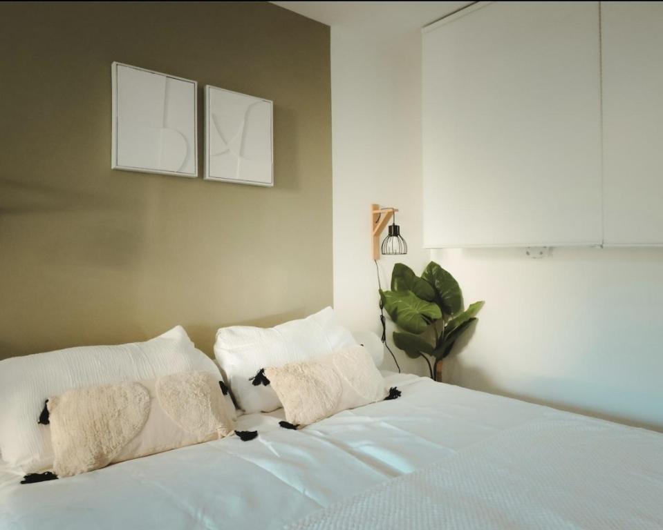 un lit avec des draps blancs et des oreillers dans une chambre dans l'établissement Home lysea, à Marseille