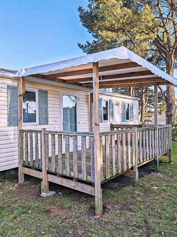 une maison avec une terrasse couverte en bois et un toit dans l'établissement Cosy Lili - Mobilhome RESPIRO - Pleine nature, plage à 250mn, à Damgan
