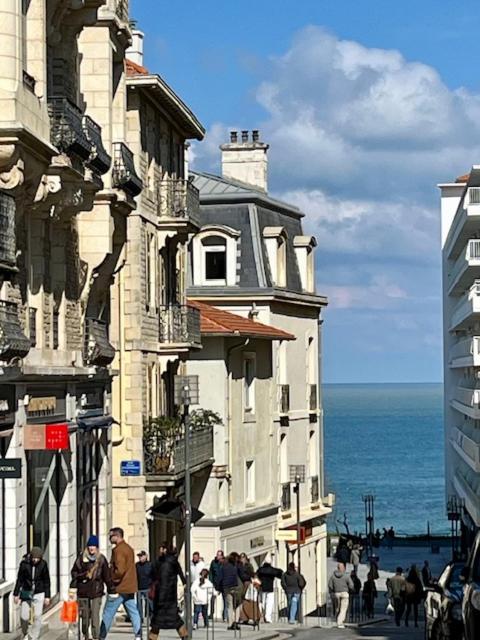 Un groupe de personnes marchant dans une rue à côté d'un bâtiment dans l'établissement Biarritz centre ville charme, à Biarritz