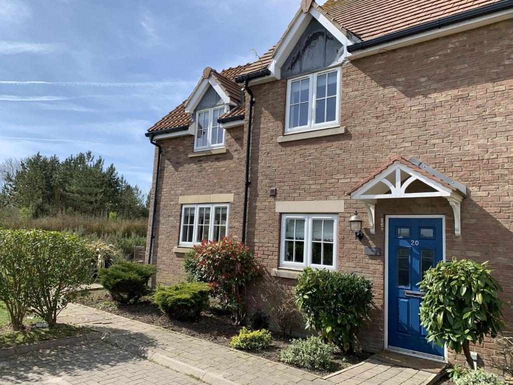 a brick house with a blue door at Caramel Cottage at The Bay Filey, sleeps 6, 2 dogs welcome for free too in Filey