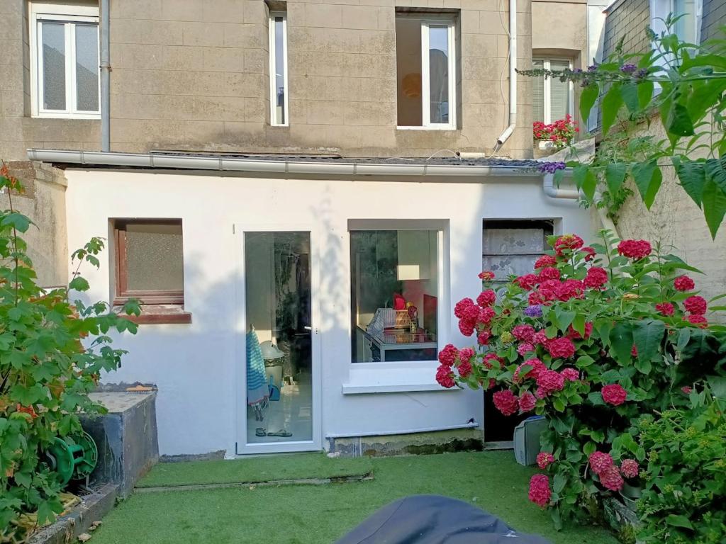 une maison avec une fenêtre et des fleurs dans la cour dans l'établissement Maison spacieuse de 2 chambres avec cour, au Tréport