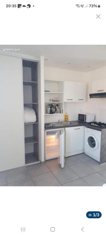 une cuisine avec des armoires blanches et une laveuse et une sécheuse dans l'établissement Le sud, à Pierre-Bénite