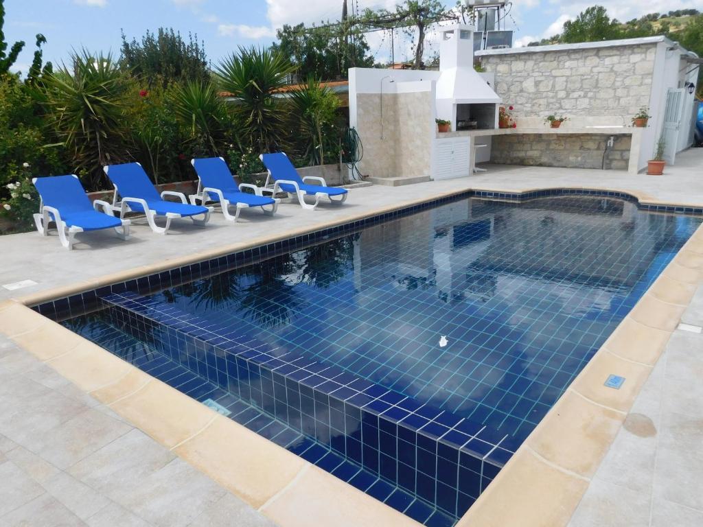 una piscina con sillas azules y una casa en Antigoni's Cottage, en Choulou