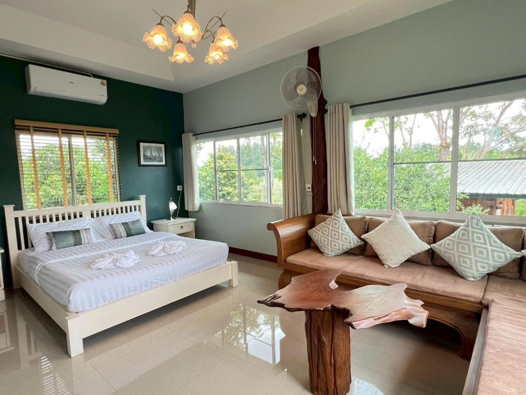 a bedroom with a bed and a couch and windows at Coco farm stay Suanphueng in Ratchaburi
