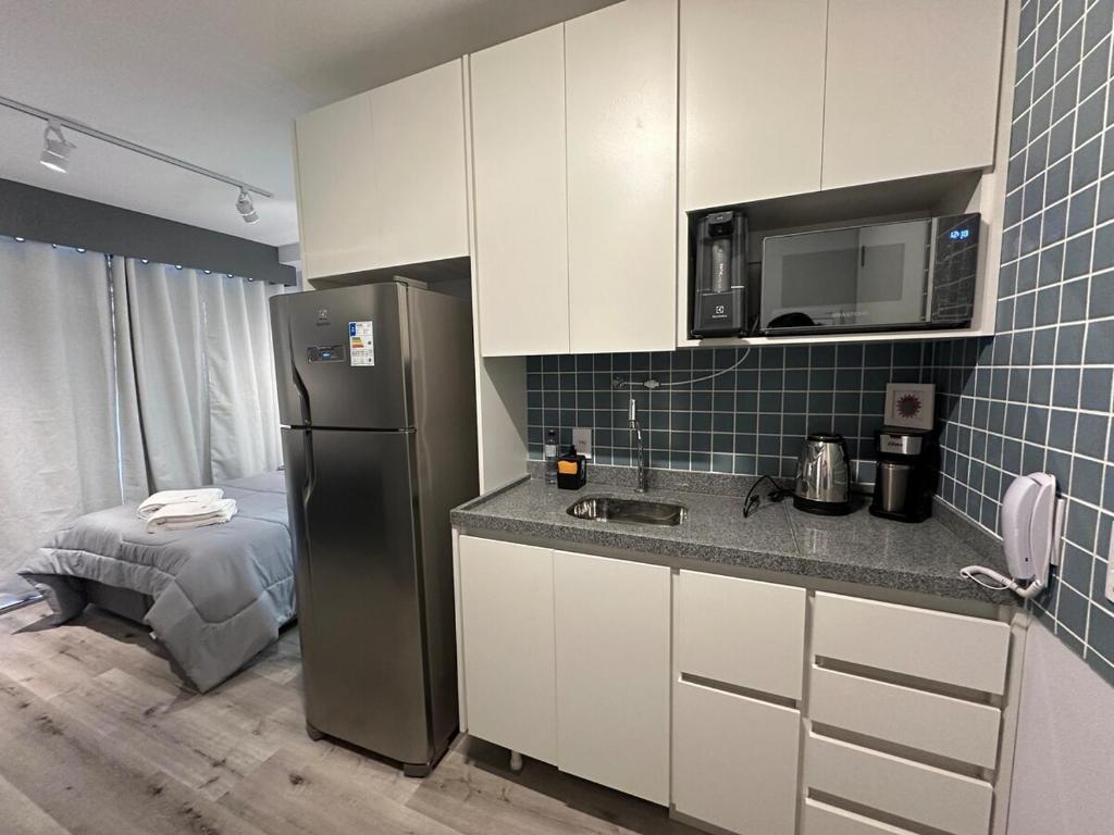 La cuisine est équipée d'un réfrigérateur et d'un évier. dans l'établissement Liberdade Loft & Comfort, à São Paulo