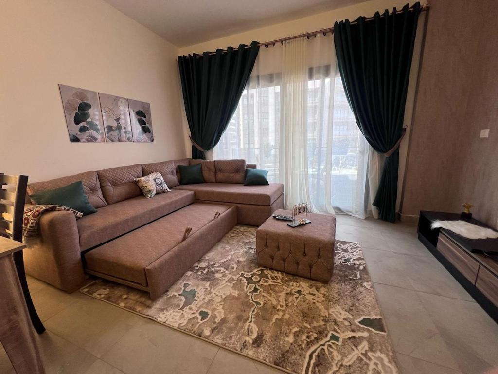 a living room with a brown couch and a large window at Luxury Living - privado, Madinaty in Madinaty