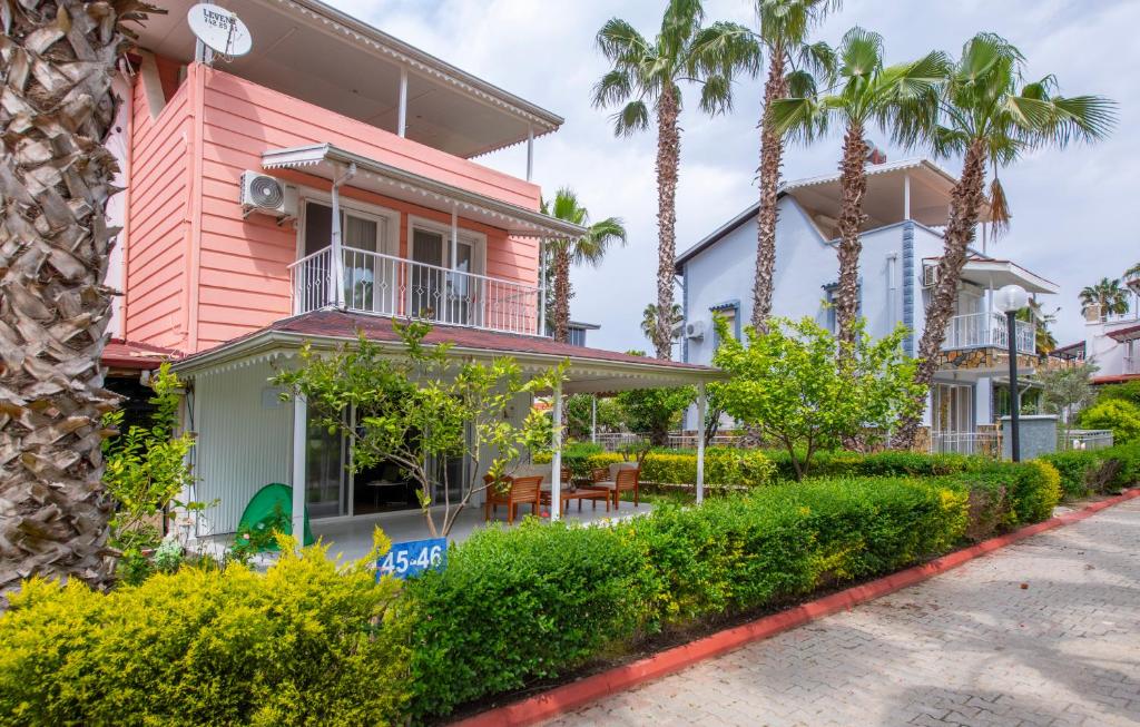 a pink house with palm trees on a street at Palladium Villa in Side