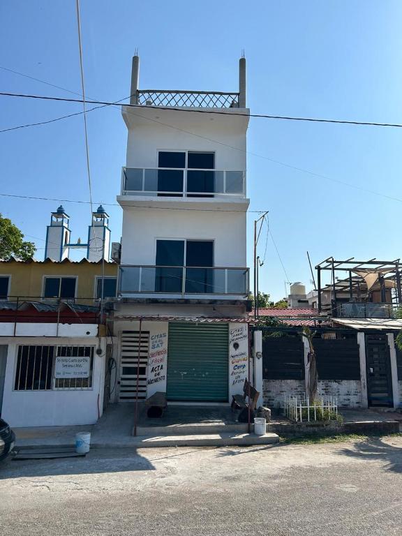 a white building with a green door and a balcony at El Amanecer de Chiltepec in Chiltepec