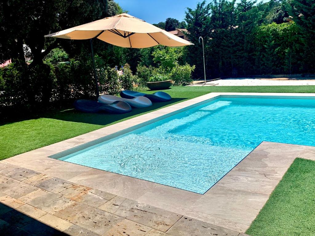 a swimming pool with an umbrella and some blue pillows at La casita de la Roca in Guadarrama