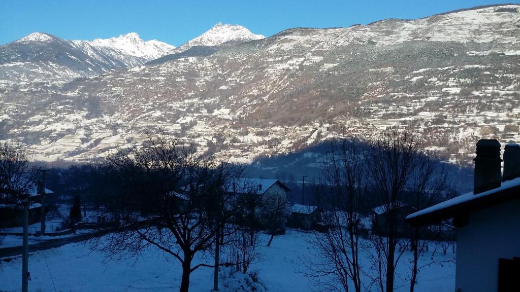 eine schneebedeckte Bergkette mit einer Stadt und Bäumen in der Unterkunft La Maison De Chantal in Fenis