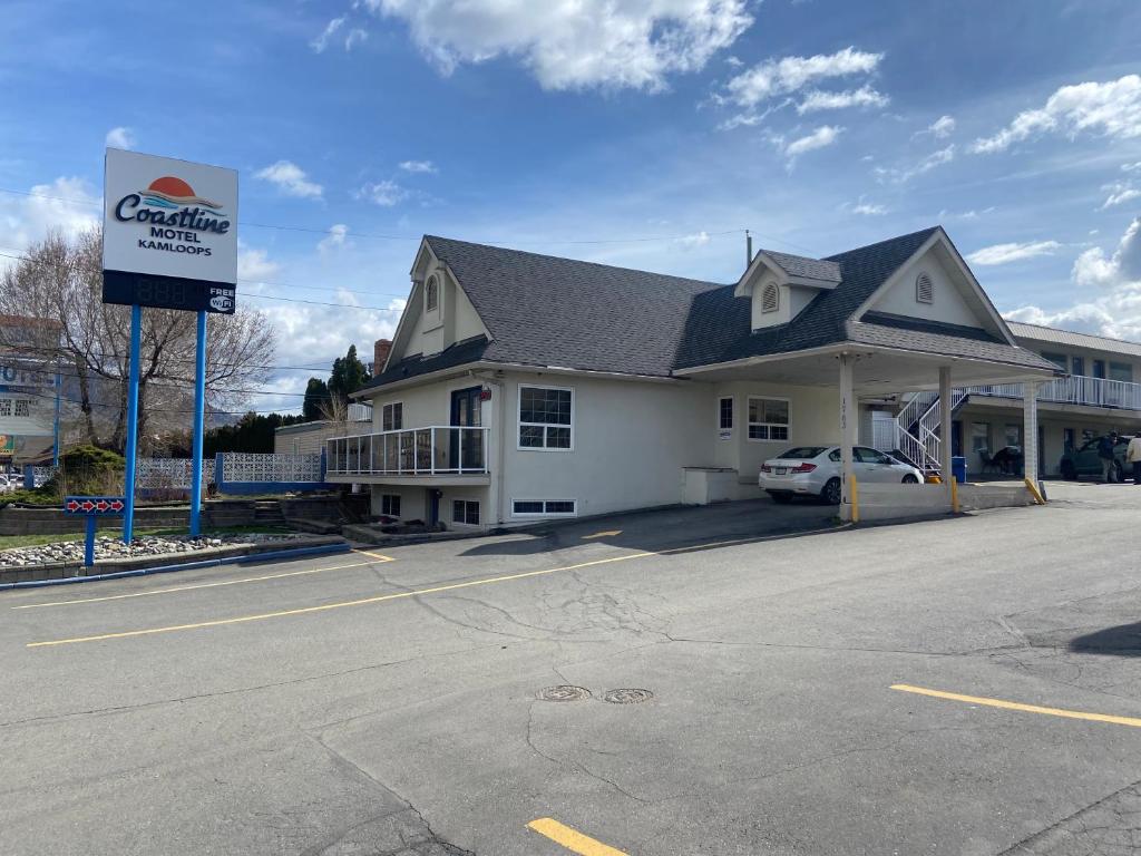 a building with a car parked in a parking lot at Coastline Motel Kamloops in Kamloops