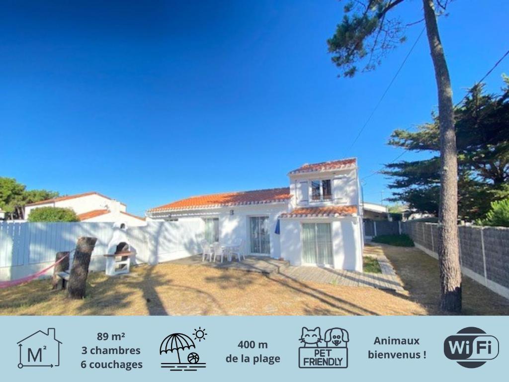 une maison blanche avec une clôture et un arbre dans l'établissement Maison rénovée, jardin clos, à 300m de la mer - 6 couchages, WiFi, animaux admis - FR-1-231-205, à Bretignolles-sur-Mer