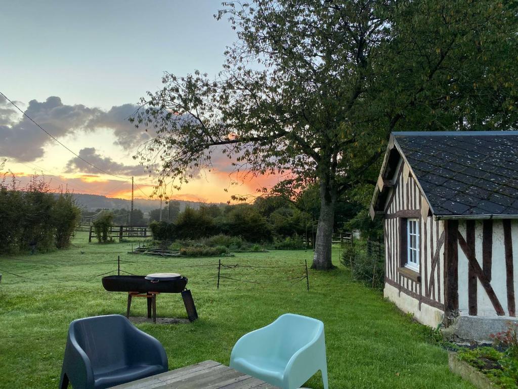 - un barbecue et deux chaises dans une cour avec un bâtiment dans l'établissement Petit gîte au coeur du haras, à Le Breuil-en-Auge