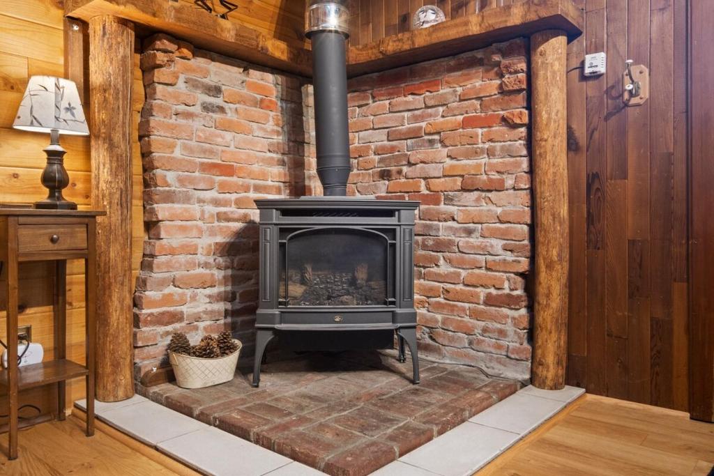 a brick wall with a fireplace in a room at Rainier's Iconic Cabin with Forest Views & Hot Tub in Ashford