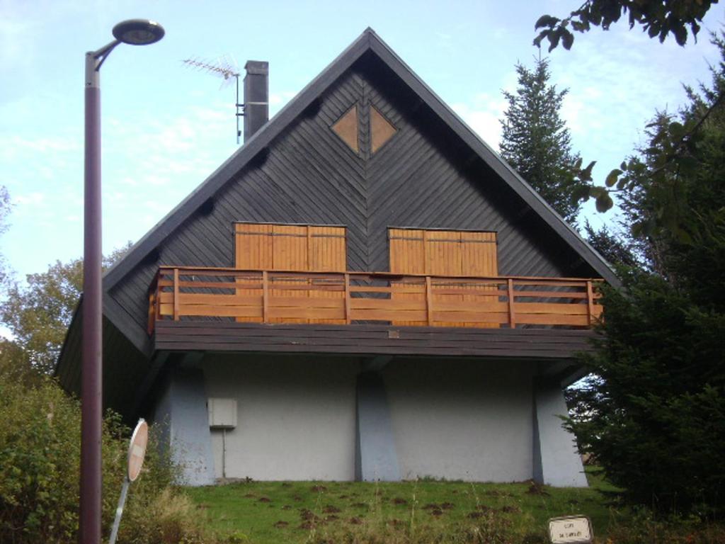 une maison avec un balcon sur le côté dans l'établissement Chalet typique proche centre station avec parking privé - FR-1-814-104, à Besse-et-Saint-Anastaise