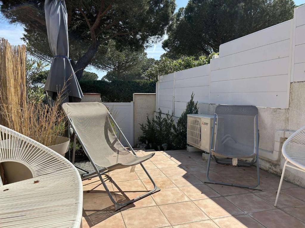 - une terrasse avec des chaises, un barbecue et un parasol dans l'établissement Maison studio mezzanine à Saint Pierre la Mer - FR-1-229D-157, à Fleury