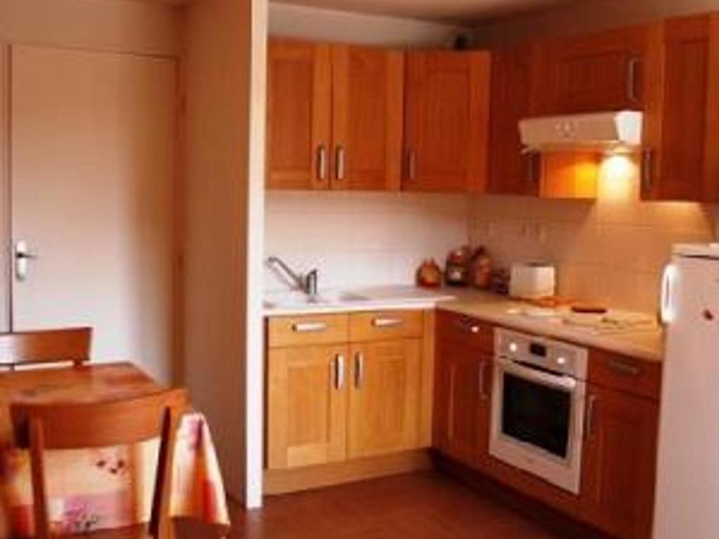 une cuisine avec des armoires en bois et un réfrigérateur blanc dans l'établissement Studio central avec parking privé à Super Besse - FR-1-814-116, à Besse-et-Saint-Anastaise