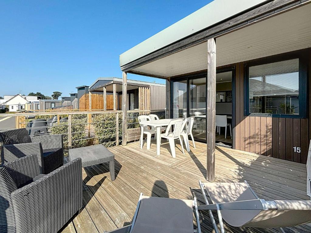 une terrasse en bois avec une table et des chaises dessus dans l'établissement Mobil-home Grand Confort à 200m plage, camping avec piscine, terrasse, WiFi inclus - 4 pers. - FR-1-361A-37, à Jullouville