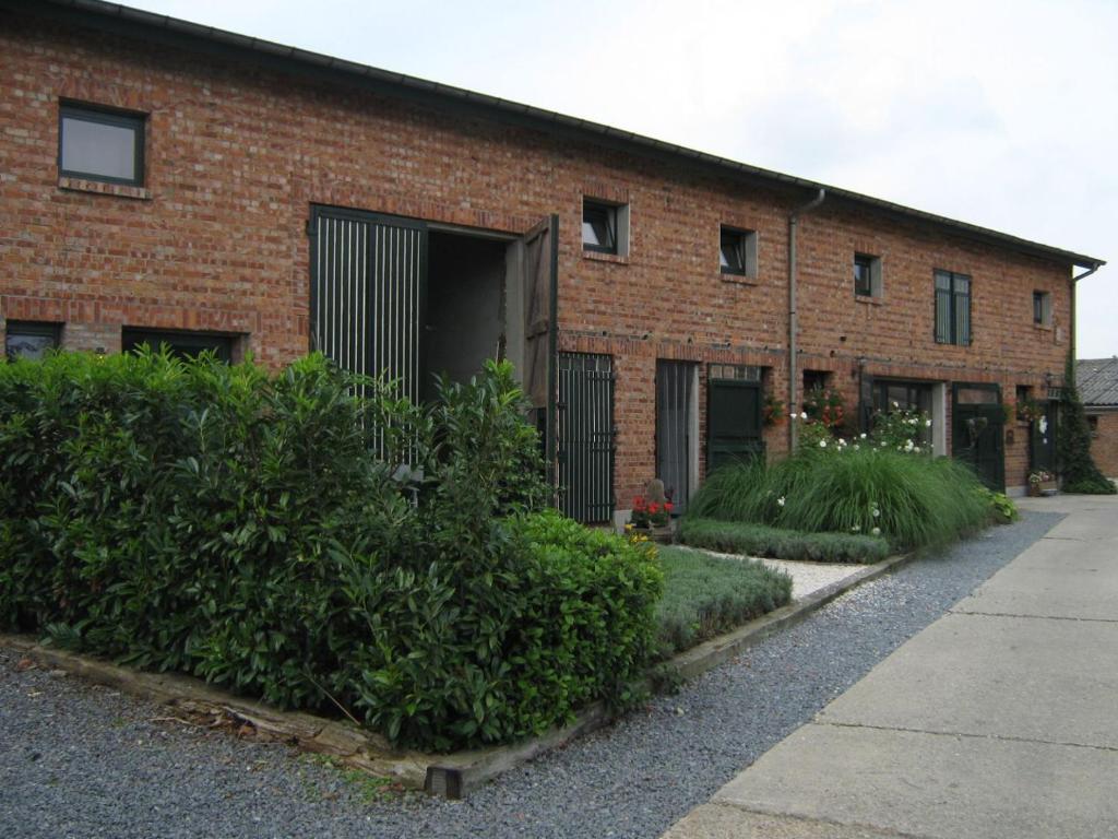 un edificio de ladrillo rojo con una puerta y algunos arbustos en B&B Euverbraeke, en Beveren