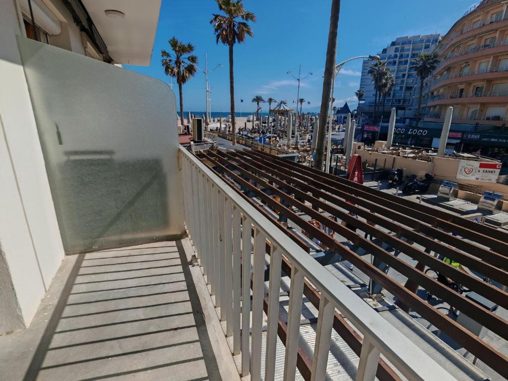d'un balcon avec vue sur la plage et les palmiers. dans l'établissement Appartement moderne avec climatisation et parking au cœur de Canet Plage - FR-1-732-91, à Canet