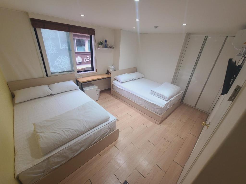 Un dormitorio pequeño con dos camas y una ventana. en Moon Sun Guesthouse, en Seúl
