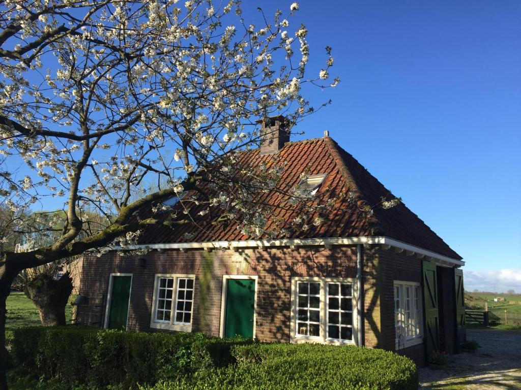 an old brick house with green doors and a tree at Louisehoeve Holiday Home in Linschoten