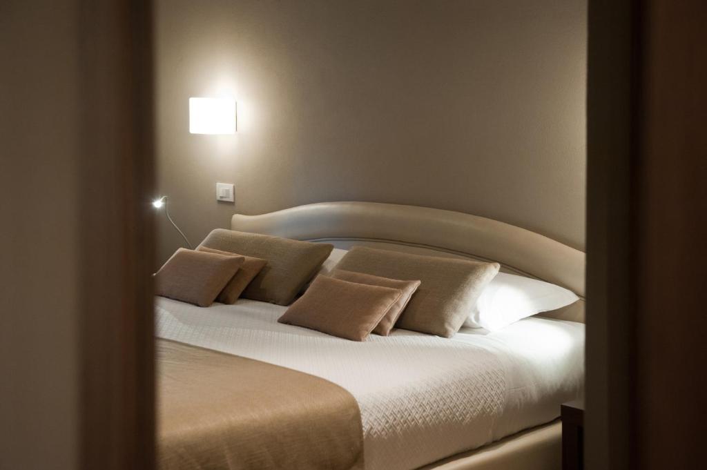 a bedroom with a bed with white sheets and pillows at Hotel Carla in Levanto