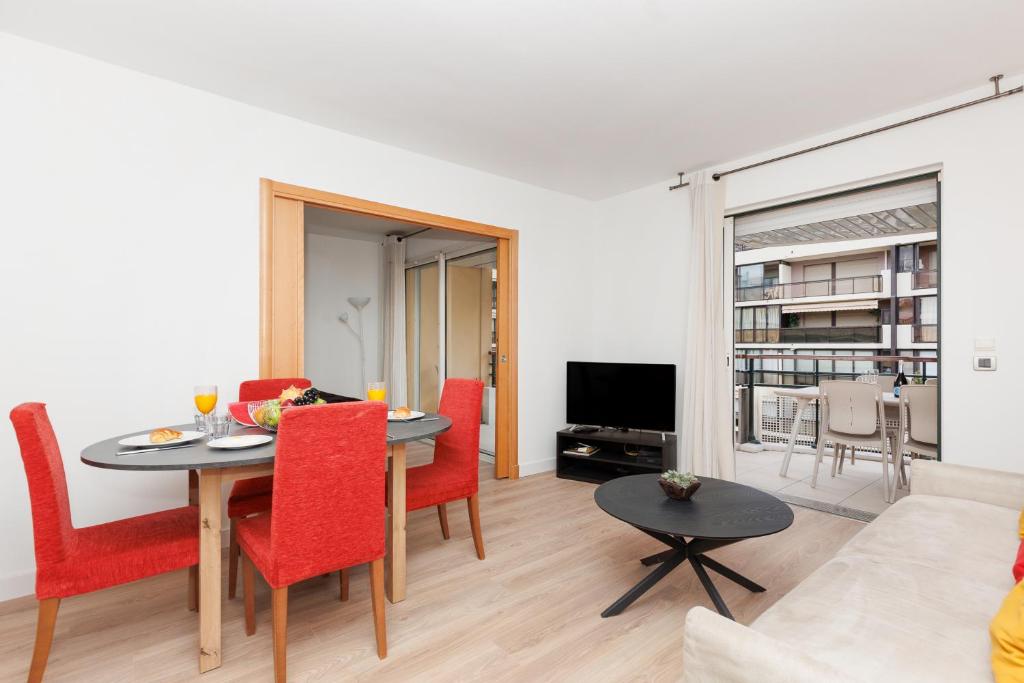 un salon avec une table et des chaises rouges dans l'établissement Pavillon Riviera YourHostHelper, à Cannes