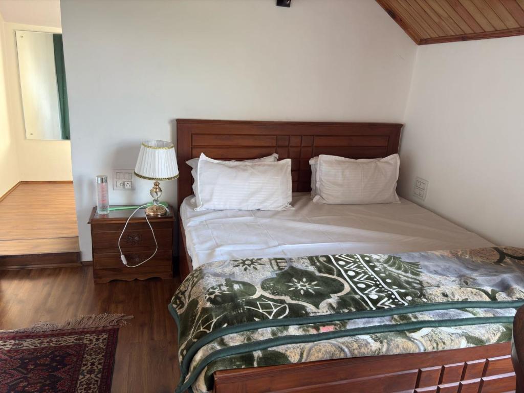 a bedroom with a bed and a table with a lamp at Tropical Green in Srinagar