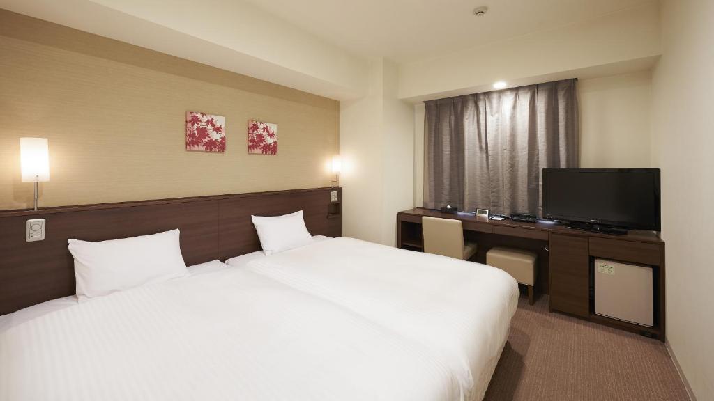 een slaapkamer met een groot wit bed en een televisie bij Sotetsu Fresa Inn Chiba Kashiwa in Kashiwa