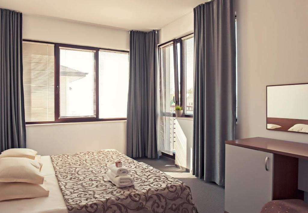 a hotel room with a bed and a desk and windows at Sea house Afrodita1-rooms in Nesebar