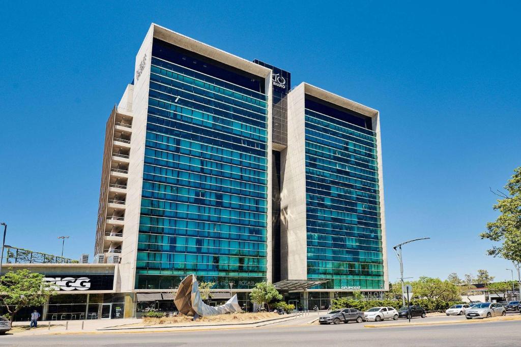 un gran edificio con ventanas de cristal en un aparcamiento en Dazzler by Wyndham Rosario, en Rosario