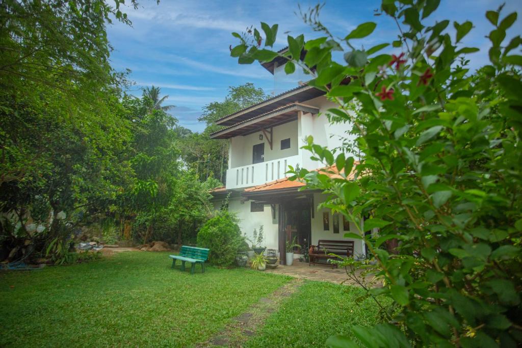 a white house with a green bench in the yard at 15 Degalla in Dodanduwa