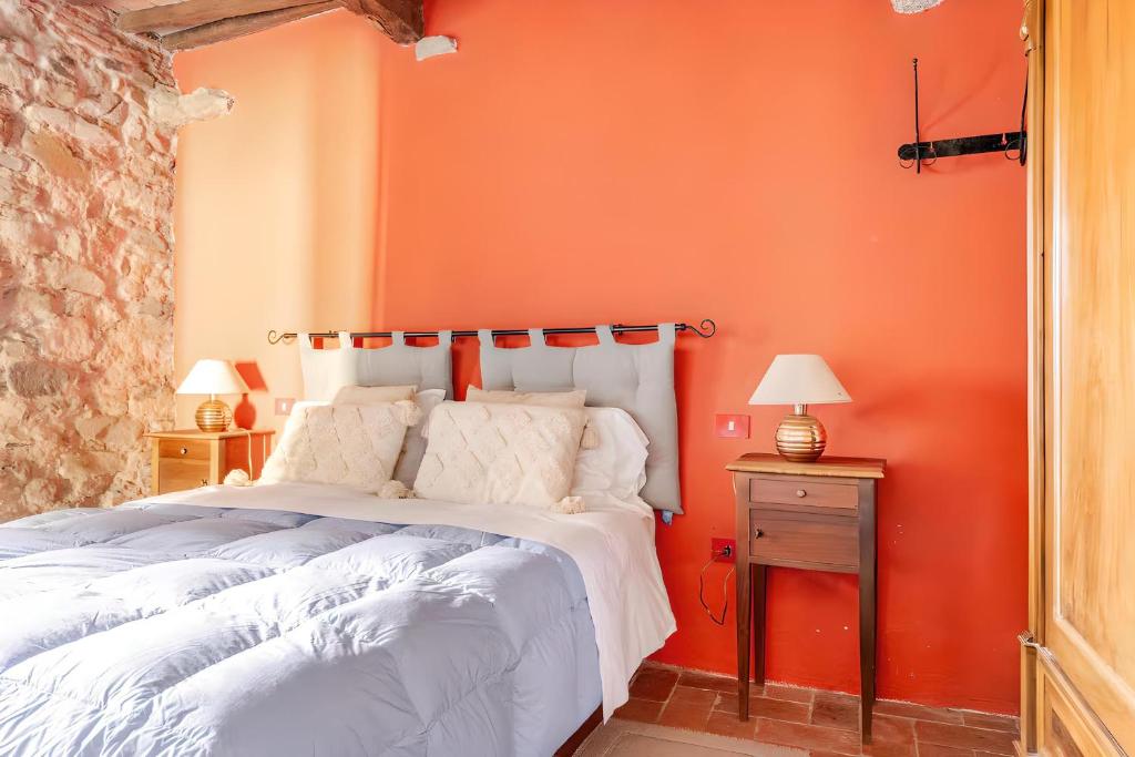 un letto in una stanza con una parete arancione di Sambuca Lodge a San Romano