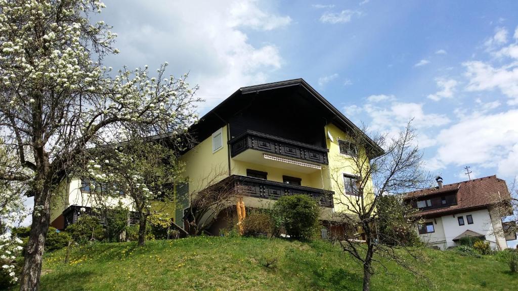 a yellow building with a black roof on a hill at Ferienwohnung Linde in Faak am See