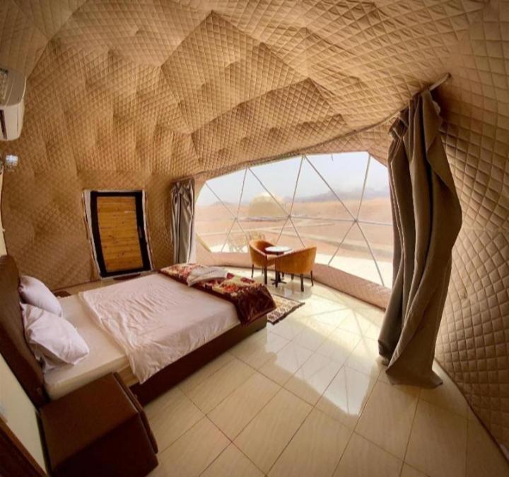 a bedroom with a large window with a bed and a table at Rum Moon Bubbles Luxury Camp in Wadi Rum