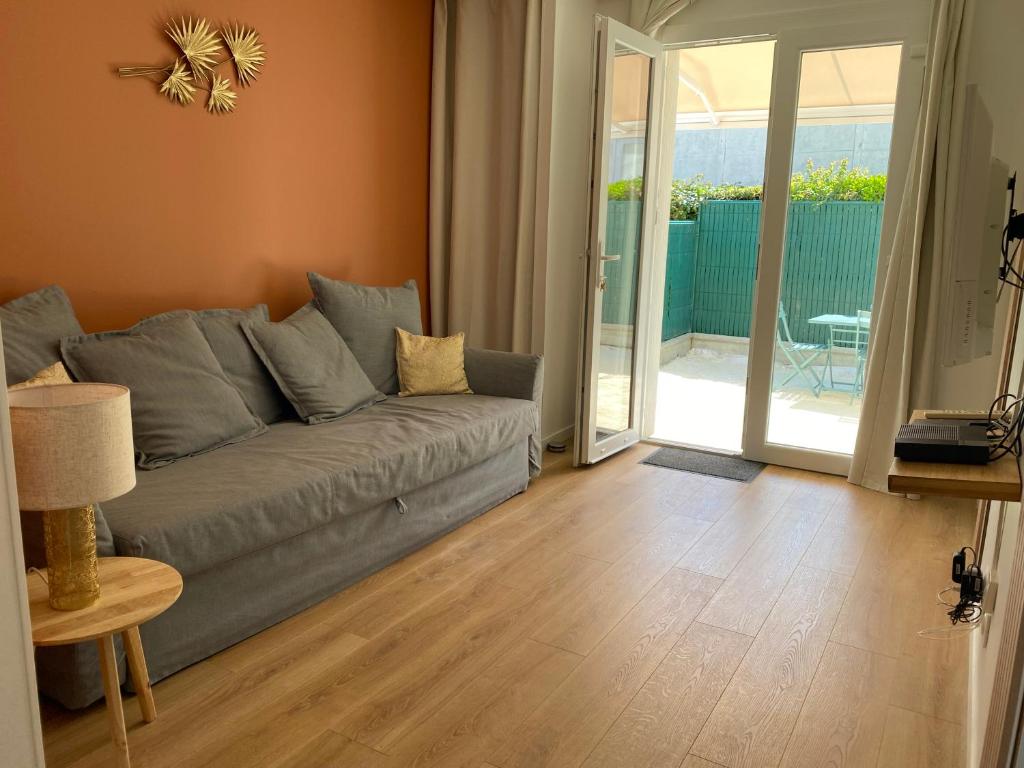 un salon avec un canapé et une porte coulissante en verre dans l'établissement T2, Jardinet, Quartier marché 10mn Plage, à Royan