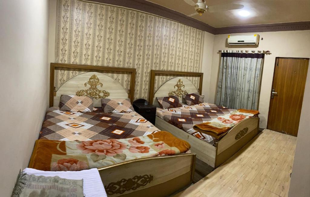 two beds are in a room with at Citi Hotel & Community Club in Faisalabad