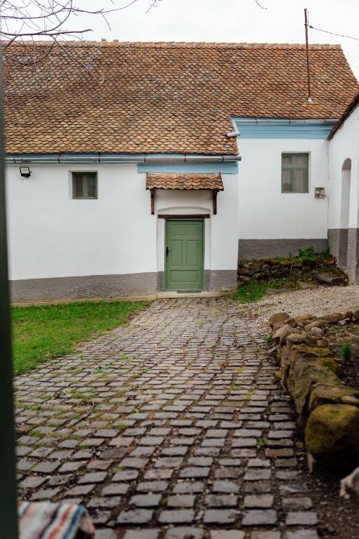 a building with a green door on a cobblestone street at Abásfalvi Vendégházak in Aldea