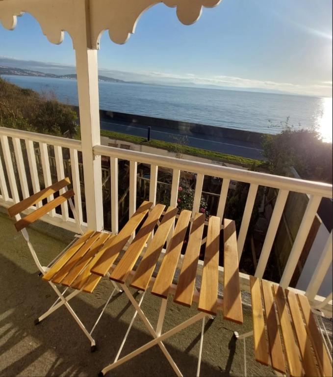 a wooden bench sitting on a balcony overlooking the ocean at Velo Club Mumbles in Oystermouth