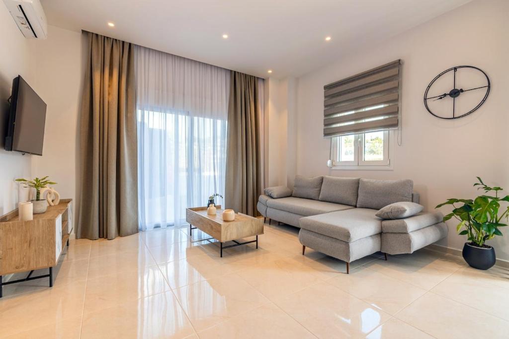 een woonkamer met een bank en een tafel bij Lume, Stylish New Apartment Near the Beach in Agia Pelagia