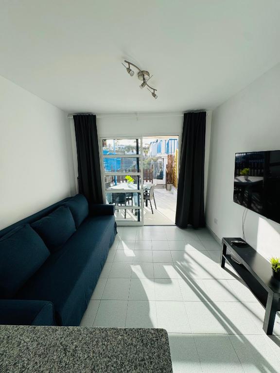 马斯帕洛马斯Bungalow Simone的客厅里有一张蓝色沙发和一台电视